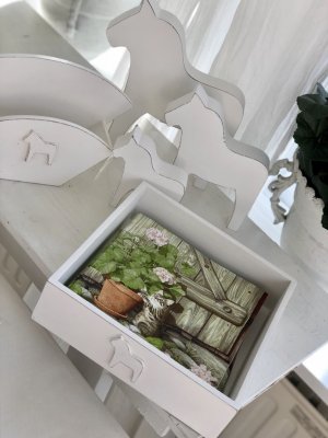 Servettställ /låda i trä vit i lantlig stil med fabriksnötta kanter. Dekorerat med en vit häst / dalahäst framtill. Lika fin att