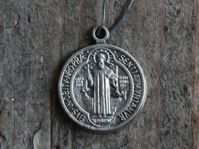 Franskt emblem/Krucifix i  rund modell med motiv , bild och text på två sidor olika. I silver färgad metall. Hänger i ståltråd.