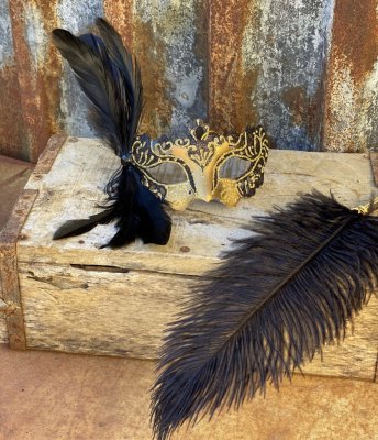 Maskerad mask i vacker gammeldags elegant modell i svart och guld med fjäder.  I modell som kan hänga men gör sig lika fint på e