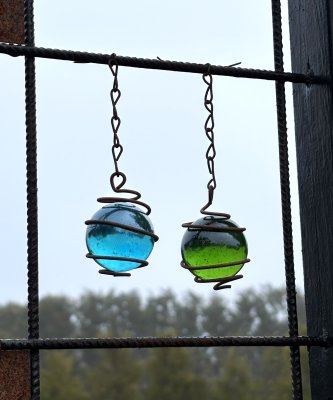 Färgad kula i glas och rost att hänga i tex armeringsnät