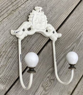 Gammeldags designad vit hängare med två krokar som är dekorerad med vita porslinsknoppar. hängarens stomme är i järn. Från chic