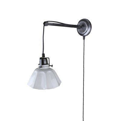 Vägglampa i antik svart med veckad vit plåt skärm. Gammeldags modell med tvinnad tyg kabel med strömbrytare. Skärmen är handmåla