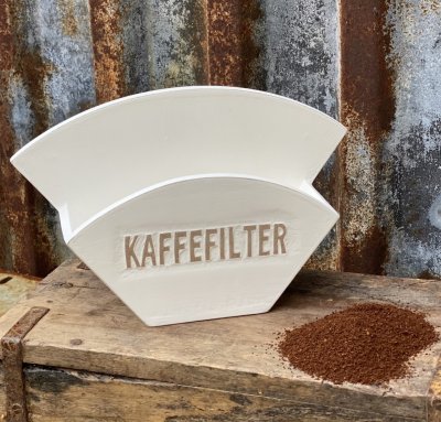 Hållare till kaffefilter i vitt trä med fabriksnötta kanter och text ” KAFFE FILTER” på fram sidan. Kan både hängas på väggen oc