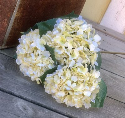 Hortensia i vit nyanser och gröna blad. Välarbetad och verklighetstrogen konstblomma. I kvist/gren modell om en blomma omgiven a