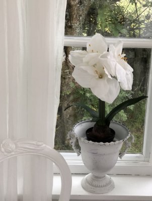 Vit vacker verklighetstrogen och välarbetad amaryllis i konstgjord modell. Med flera vita klockor blommor och gröna blad. Står i