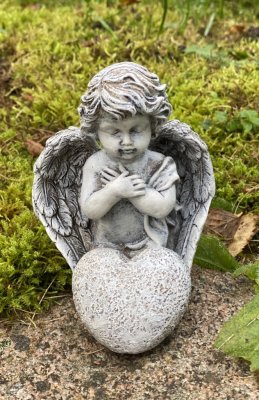 Bedjande ängel som sitter ner på knä, med hjärta och stora vingar. Går i en grå vit nyans som liknar sten. Detalj full och välar