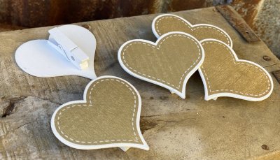 Hjärtan i guld och vitt med nypa på baksidan så man kan använda dom vid tex dukning eller att stätta på paket. Tillverkad i trä