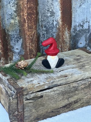 Sittande tomte i trä med röd luva 