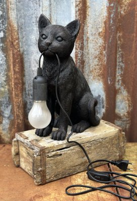 Vacker, rolig och söt lampa i annorlunda modell. Sittande katt med lampans sladd i munnen. Går i en antik svart / brun nyans. Ti