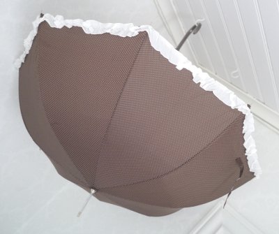 Lyxigt brunt paraplymodell Biscuit dekorerat med vita små prickar . I ytterkant runt om vågig vacker volang i vitt, samt en rose