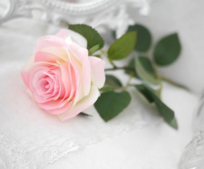 Vacker rosa verklighetstrogen konstblomma ros i utslagen vacker och romantisk modell med skaft och blad. Att dekorera med ensam