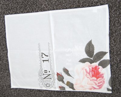 Vacker vit handuk/köks handuk med färgat tryck av en ros samt text nertill på sidan. Upphägnings öggla på sidan i ena hörnet upp