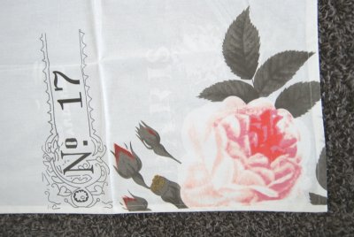 Vacker vit handuk/köks handuk med färgat tryck av en ros samt text nertill på sidan. Upphägnings öggla på sidan i ena hörnet upp
