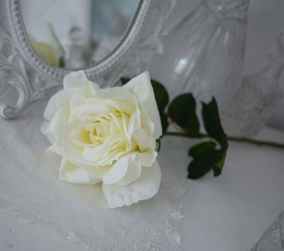 Cream vit ros i utslagen större modell med lång stjälk och gröna blad. Välarbetad vacker konstgjord blomma som gör sig lika bra