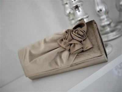 Vacker och elegant sammets  väska med rosor som en rosrosett. I stelare rundad modell med magnetlås. Finns i flera olika nyanser