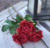 Vacker röd verklighetstrogen konstblomma ros i utslagen vacker och romantisk modell med skaft och blad. Att dekorera med ensam