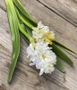 Vacker vit utslagen hyacint med flera gröna blad. Verklighetstrogen och välarbetad konstgjord blomma i större modell med verklig