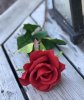 Vacker röd verklighetstrogen konstblomma ros i utslagen vacker och romantisk modell med skaft och blad. Att dekorera med ensam