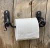 Hållare till toalettpapper formad som en större hasp. I svart smide . Modell som både kan sättas på väggen och under en hylla el