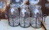 Glas vaser / flaskor som står i en nätad rost brun korg med ring formade handtag. Finns om två modeller -Två flaskor -Tre flasko
