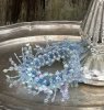 Ljusmanschett /servettring med blå pärlor. Pärlorna är trädda på elastisk tråd och kan därav anpassas efter storlek på ljuset el