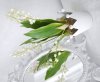 Vacker och verklighetstrogen konstgjord planta med många vita liljekonvaljer och gröna bland. Mossbeklädd nertill virad med dis