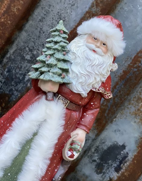 Vacker röd tomte/ jultomte med mjuka inslag av grönt och vitt. Tomten har en glittrande gran i handen och päls kantad kappa samt