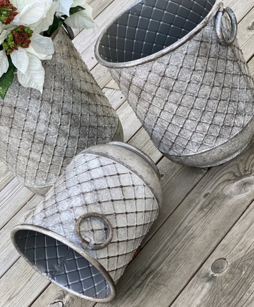 Tunna/kruka/urna i större modell med ledade handtag på sidorna. Lätt mönstrad och rundad i modellen, tillverkad i metall och går