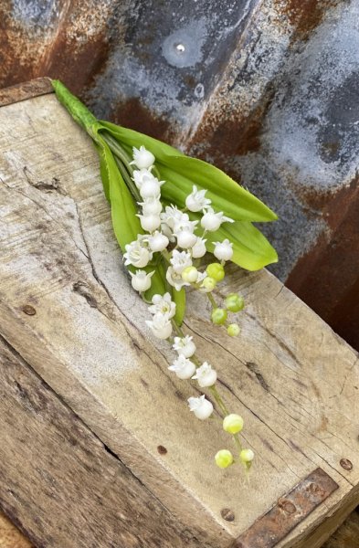 Vacker vit vår bukett med Liljekonvaljer i modell med fler blommor och gröna blad. Verklighetstrogna konstblomma välarbetad des