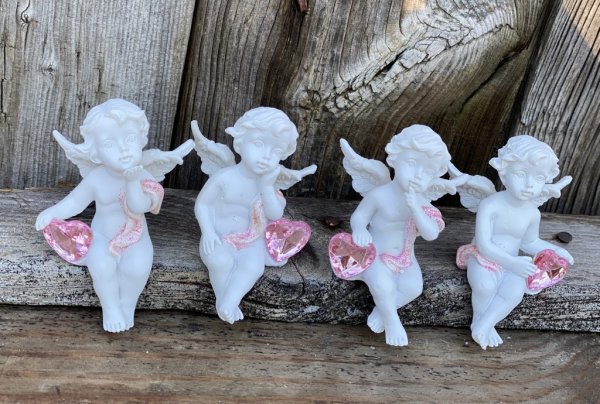 Vacker vit ängel som sitter på kant och dinglar med benen. Med rosa detaljer och en rosa diamant liknande hjärta. Finns i fyra o