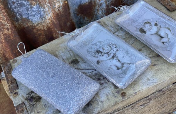 Julgranskula / dekorationskula i avlång modell med ängelmotiv. Finns i tre olika motiv -Pussande änglar -Ängel med blomsterkrans