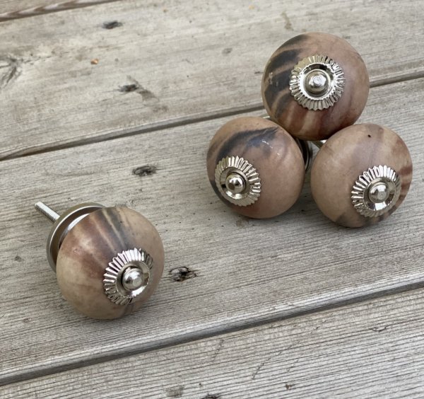 Rund brun knopp med melerat svart inslag, likt marmor mönster som är olika på alla knoppar. Stomme och krage i silver. En levand