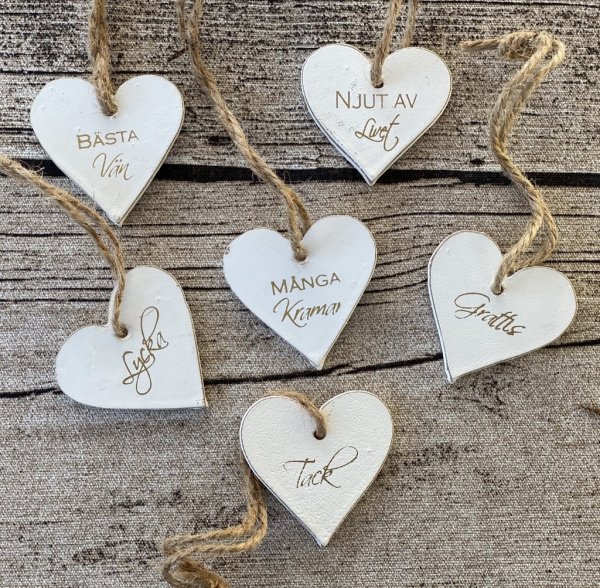 Små vita hjärtan i trä med guld text. finns i sex olika modeller - Tack - Njut av livet - Grattis - Lycka - Bästa vän - Många kr