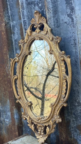 Vacker spegel i guld. Oval i modellen med snirklig barock ram. Designad i en antik och gammeldags stil. Modellen formen på speg
