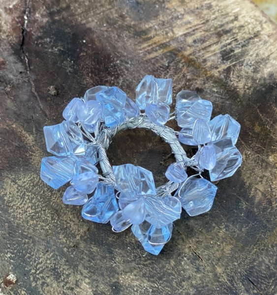 Ljusmanschett med ljusblåa pärlor virat på silverfärgad metall tråd. Att ha runt ett ljus eller använda som servettring vid dukn