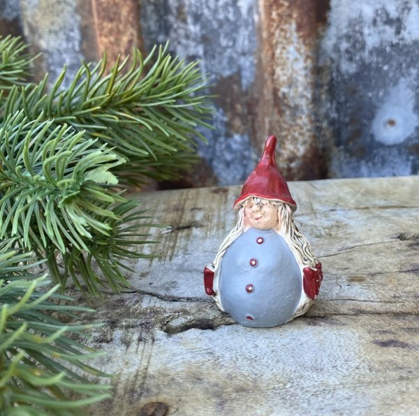 Söt tomte flicka i mindre modell. Rund i kroppen med röd luva och långa flätor prydda med rosetter. Detaljrik och välarbetad i m