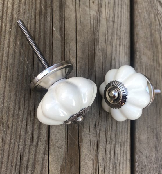 Blomformad porslinsknopp lätt cream vit med krage i silver. Mäter Längd 8cm Bredd ca4,4cm Säljes per styck en och en