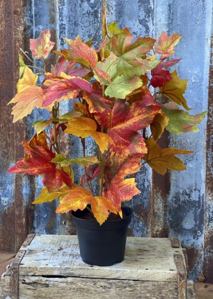 Vacker verklighetstrogen kruka med höstlöv lönn löv i färgrika blandade nyanser. Välarbetad och verklighetstrogen konstgjord mod