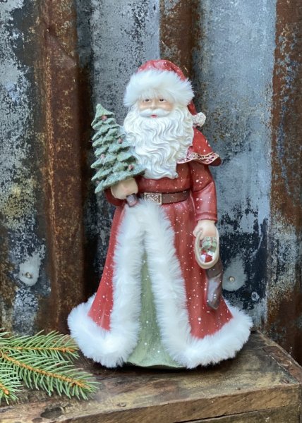 Vacker röd tomte/ jultomte med mjuka inslag av grönt och vitt. Tomten har en glittrande gran i handen och päls kantad kappa samt