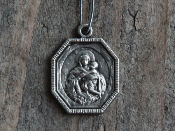 Franskt emblem/Krucifix i kantig modell med motiv , bild och text på två sidor olika. I silver färgad metall. Hänger i ståltråd.
