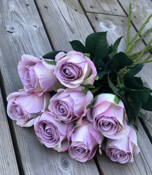 Vacker lila ros med gröna blad. Välarbetad vacker konstgjord ros med hög verklighets trogen känsla. Lika vacker ensam som i en b