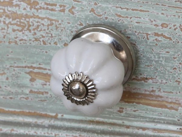 Klassisk vit porslins knopp i veckad modell med silver färgad metall krage. I mindre modell. Dekorerad med Chic Antique emblem i