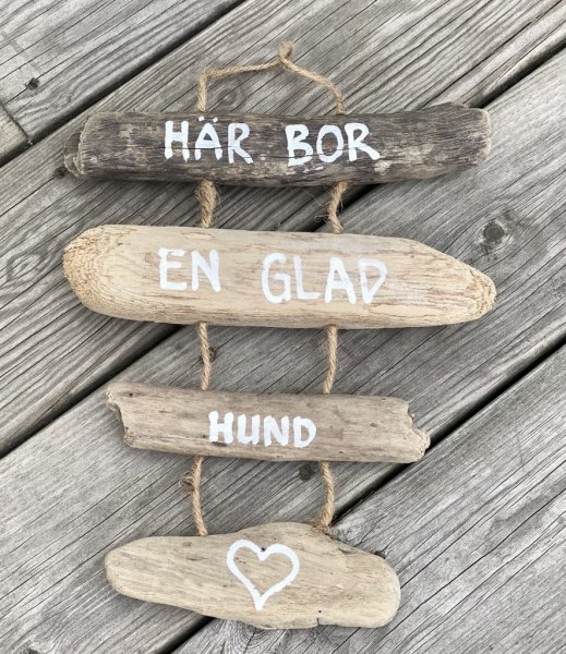 Vacker skylt i hängande drivved. Med text på drivvedsbitarna som sitter ihop med snören. Finns i två modeller/texter. -Här bor e