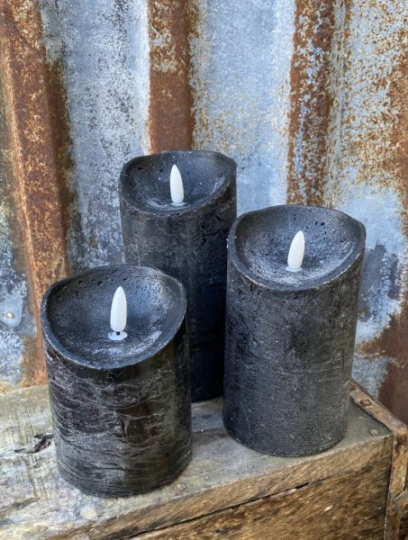 Svarta cylinderformade ljus/led ljus , riktigt vaxljus därav skiftande i mörka och ljusa nyanser. Batteri drivna med timer funkt