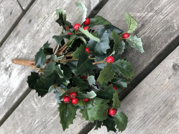 Järnek om flera kvistar gröna blad och röda bär. Välarbetad och detaljrik i verklighetstrogen konstgjord modell. Att pynta och