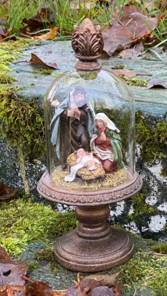 Vacker julkrubba med Josef, Maria och Jesus barnet. Under en glaskupa som står på ett vackert dekorerat fat på fot. Kupan sitter