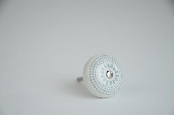 Vit rund porslins knopp med grått retro mönster likt en blomma. Med silver färgad metall stomme. I grepp vänlig modell.