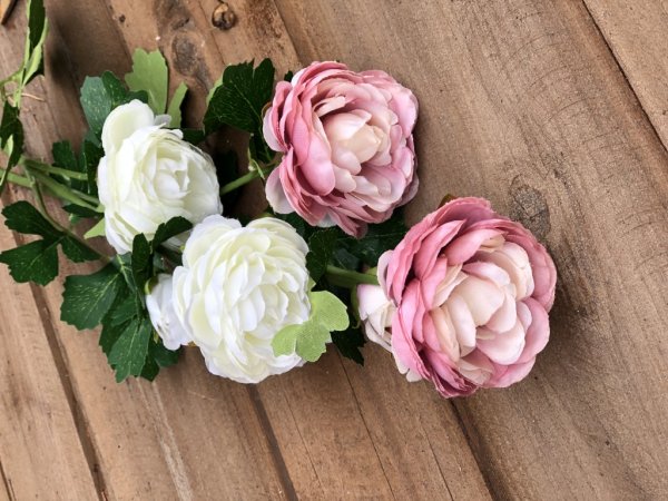 Vacker ranunkel blomma med gröna blad. Välarbetade i verklighetstrogen konstgjord modell. Går i mjuka nyanser av rosa och cream
