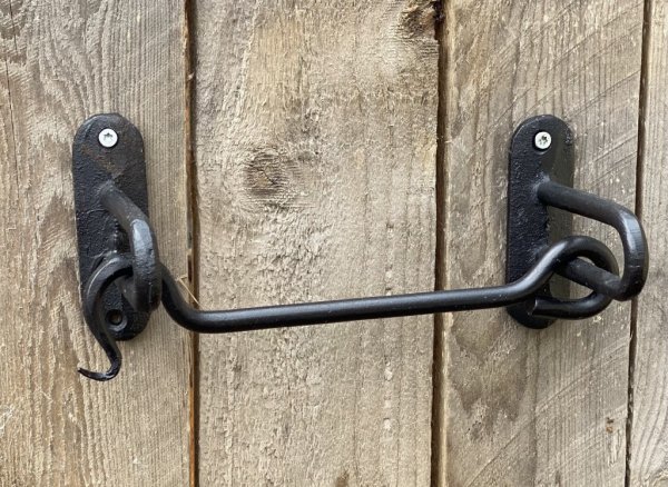 Hållare till toalettpapper formad som en större hasp. I svart smide . Modell som både kan sättas på väggen och under en hylla el