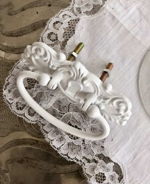 Vackert och detaljfullt handtag i gammeldags modell. I vit målad metall. Passande som handtag eller knopp på lådor skåp eller li